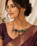 Statement necklace and matching earrings worn with maroon saree; gold-tone multi-stone design