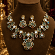 Gold-tone necklace set with green center pendant, oval drops, and matching earrings