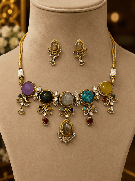 Gold-tone necklace set on bust with oval and round colored stones and dangling charms