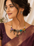 Statement necklace and matching earrings worn with maroon saree; gold-tone multi-stone design