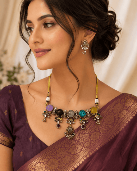 Statement necklace and matching earrings worn with maroon saree; gold-tone multi-stone design