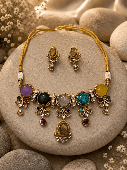 Gold-tone statement necklace and stud earrings with purple, blue, and black stones