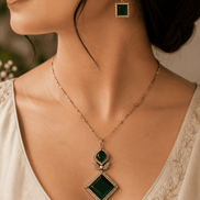 Gold pendant necklace set with emerald green teardrop and diamond pendant on model