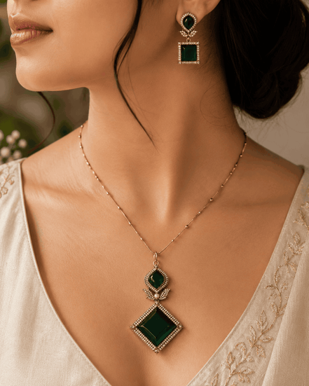 Gold pendant necklace set with emerald green teardrop and diamond pendant on model