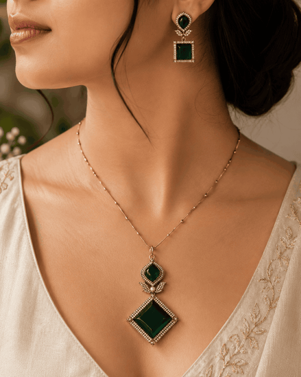 Gold pendant necklace set with emerald green teardrop and diamond pendant on model