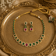 Gold-tone necklace with green stones and red accents with matching stud earrings