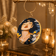Round blue illustrated clutch bag with gold-tone chain and portrait front