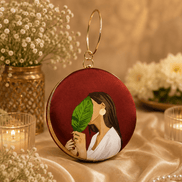 Round maroon illustrated clutch bag with gold-tone chain and leaf portrait front