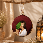 Round maroon illustrated clutch bag with gold-tone chain and leaf portrait front