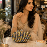 Multicolor beaded clutch with gold-tone top clasp and chain handle, held on table