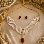 Gold-tone pearl necklace with maroon center drop pendant and beaded tassel ends