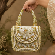 Beige beaded shoulder bag held by top handles, detailed beadwork and charm accents