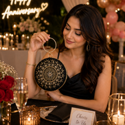 Black embroidered circular ring clutch with gold-tone ring handle, held at shoulder height.