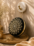 Black embroidered circular ring clutch with gold-toned floral detailing and ring handle.
