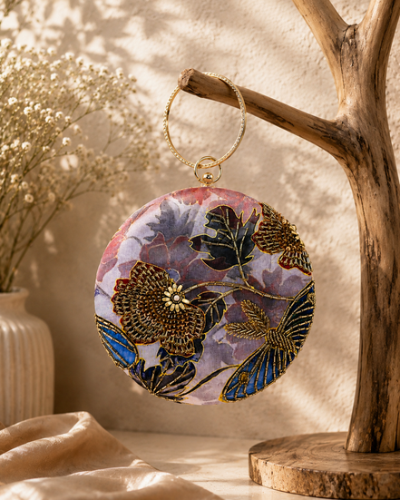Multicolor embroidered ring clutch with circular top handle and gold-toned ring hardware.