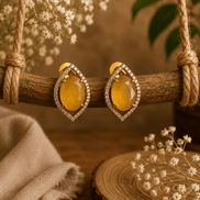 Yellow teardrop halo stud earrings with pave crystal border, gold-tone setting.