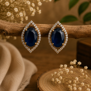 Dark blue teardrop halo stud earrings with pave crystal border, gold-tone setting.
