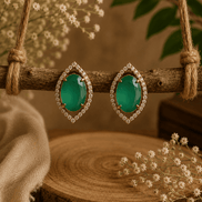 Green teardrop halo stud earrings on display stand, pavé crystal bezel, gold-tone.