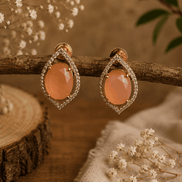 Peach teardrop halo stud earrings with pavé crystal border, gold-tone setting.