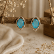 Light blue teardrop halo stud earrings with pavé crystal border, gold-tone setting.