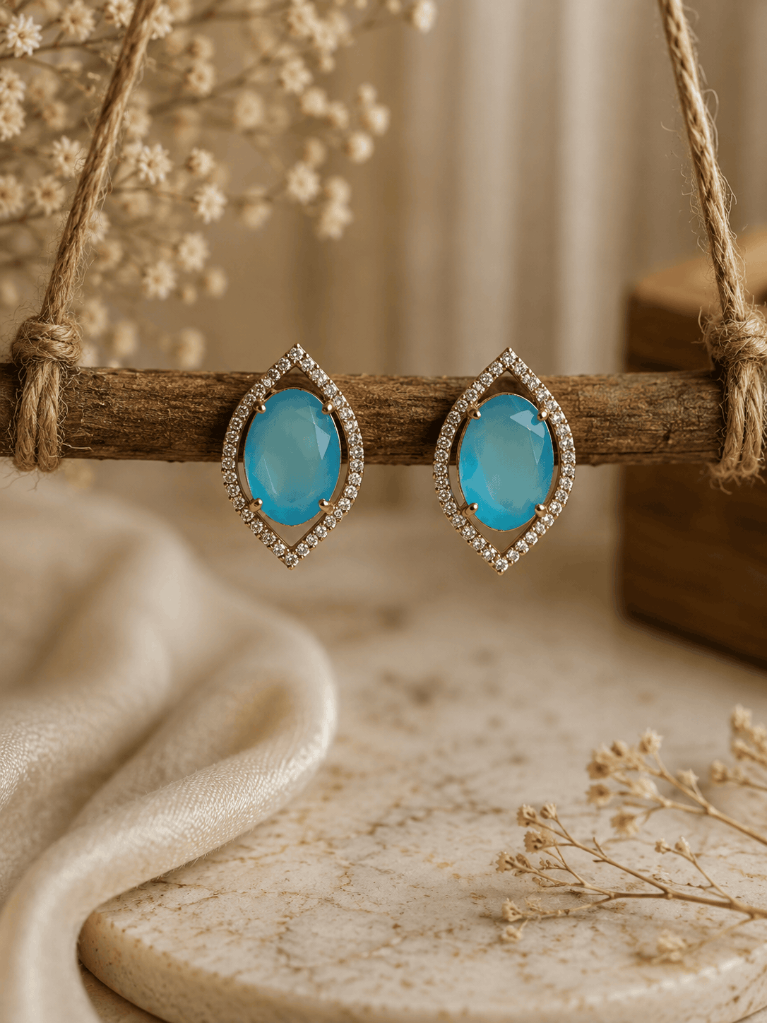 Light blue teardrop halo stud earrings with pavé crystal border, gold-tone setting.