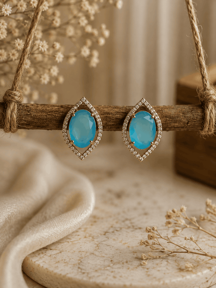 Light blue teardrop halo stud earrings with pavé crystal border, gold-tone setting.