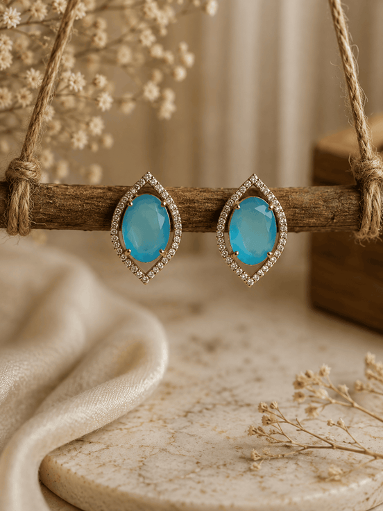Light blue teardrop halo stud earrings with pavé crystal border, gold-tone setting.