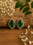 Green teardrop halo stud earrings with pave crystal border, gold-tone setting.
