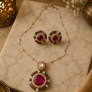 Gold-tone jewelry set with round stud earrings and a large circular pendant with red center