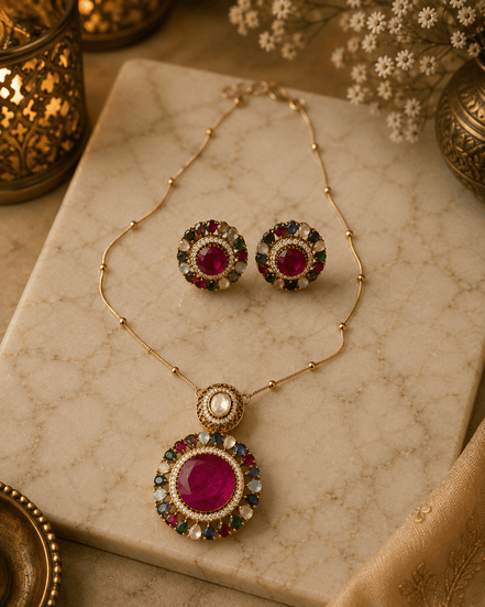Gold-tone jewelry set with round stud earrings and a large circular pendant with red center