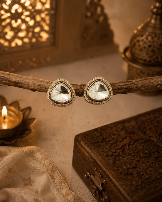 Gold-tone crystal stud earrings with round halo bezel and faceted clear center.