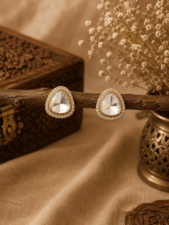 Gold-tone round crystal stud earrings with sparkling halo border and bezel setting.