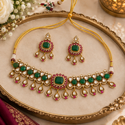 Green kundan necklace with ruby-red drops, paired with matching dangling earrings.