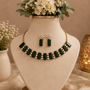 Emerald green gemstone choker and matching drop earrings set on display bust