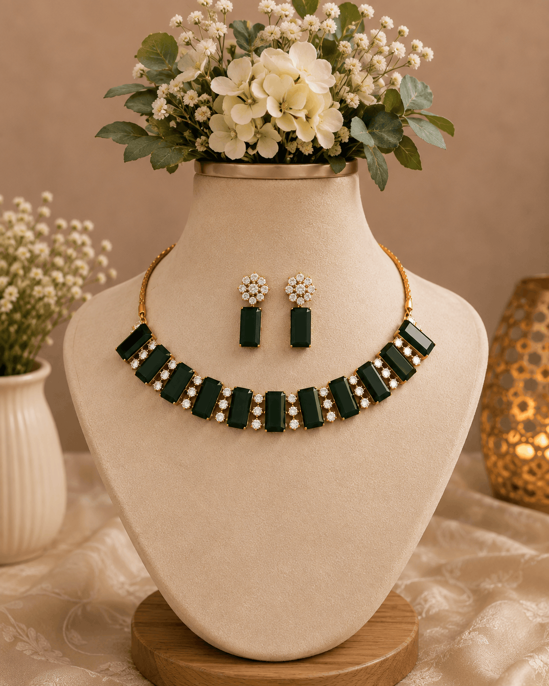 Emerald green gemstone choker and matching drop earrings set on display bust