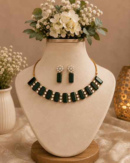 Emerald green gemstone choker and matching drop earrings set on display bust