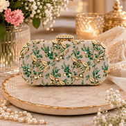 Embroidered beaded clutch bag with green and yellow floral motifs on light blue base.