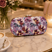 Floral sequin clutch bag in purple and pink with decorative bow-like beads.