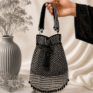 Black beaded potli bag with bow accent, drawstring and round tassel fringe.