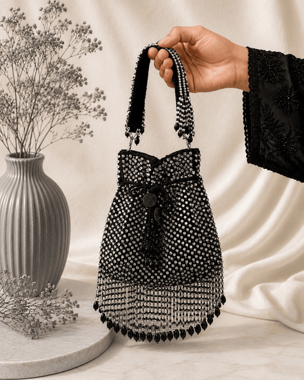 Black beaded potli bag with bow accent, drawstring and round tassel fringe.