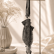 Black beaded potli bag hanging on a stand with long tassels and fringe.
