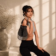 Black beaded potli bag with tassels, worn over a dark outfit.