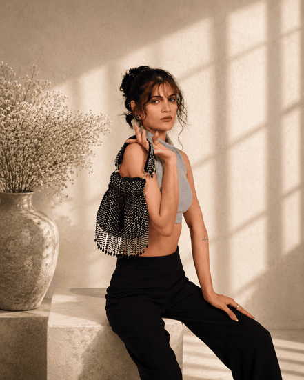Black beaded potli bag with tassels, worn over a dark outfit.