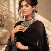 Black beaded potli bag in hand, paired with layered jewelry and a sheer drape.