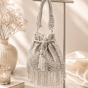 Silver beaded potli bag displayed on stand with tassel trim and drawstring.