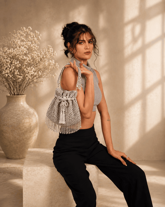 Silver beaded potli bag with drawstring and dangling tassels.
