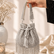 Silver beaded potli bag held up by the handle, tassels visible.