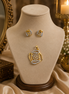 Gold-tone pendant necklace with blue crystal stud earrings on display bust
