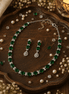 Emerald-green beaded necklace and drop earrings with glossy stones and silver settings
