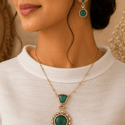 Emerald pendant necklace set with gold chain and matching drop earrings on model